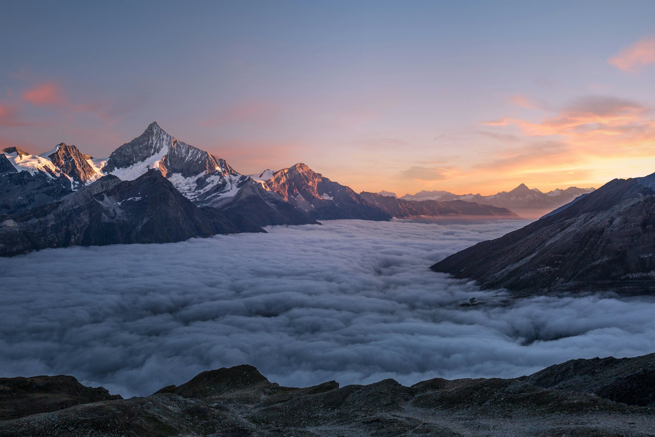 Cumbres de montaña emergiendo sobre un mar de nubes al atardecer